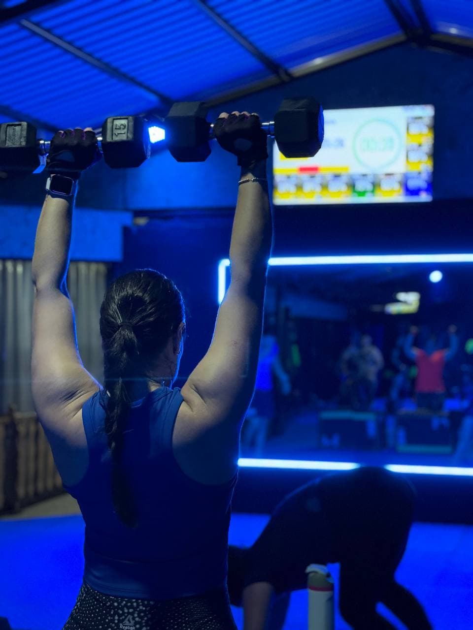 Persona levantando mancuernas sobre la cabeza